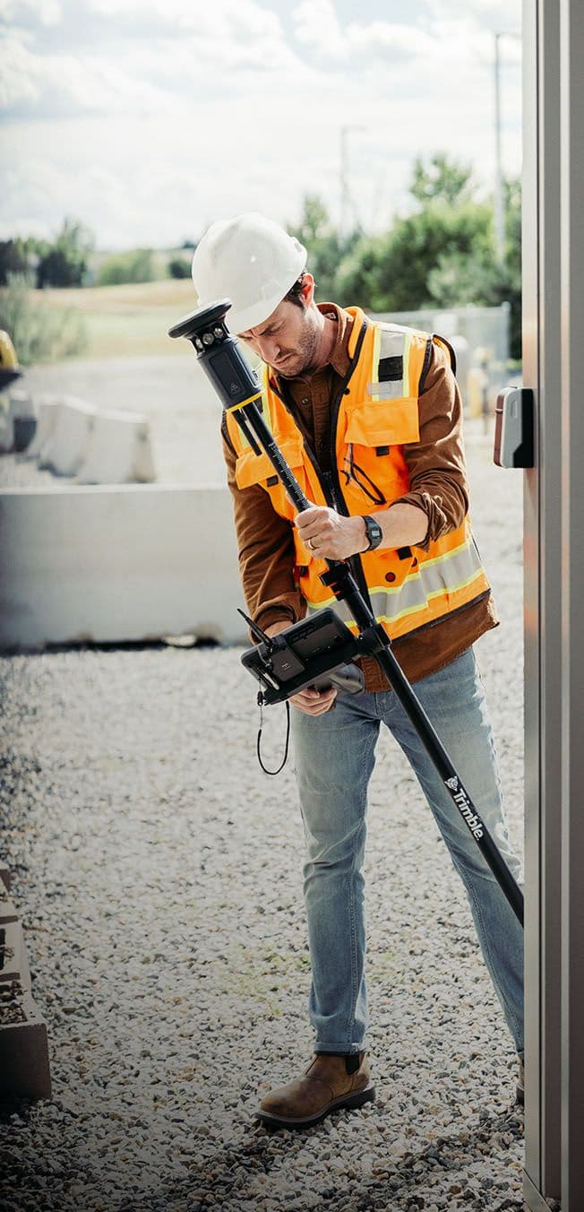 Man met veiligheidskleding en een trimble product op de schouder